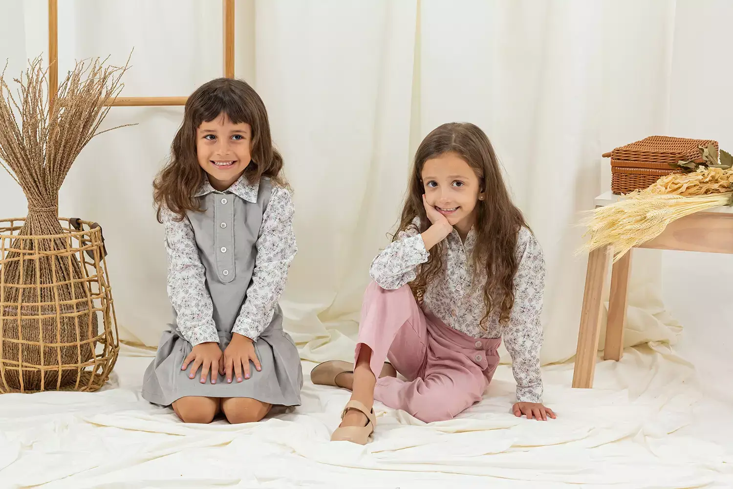 Duas meninas sentadas em cenário no chão com roupas da Cris Moretti Moda Infantil - Just Real Moms
