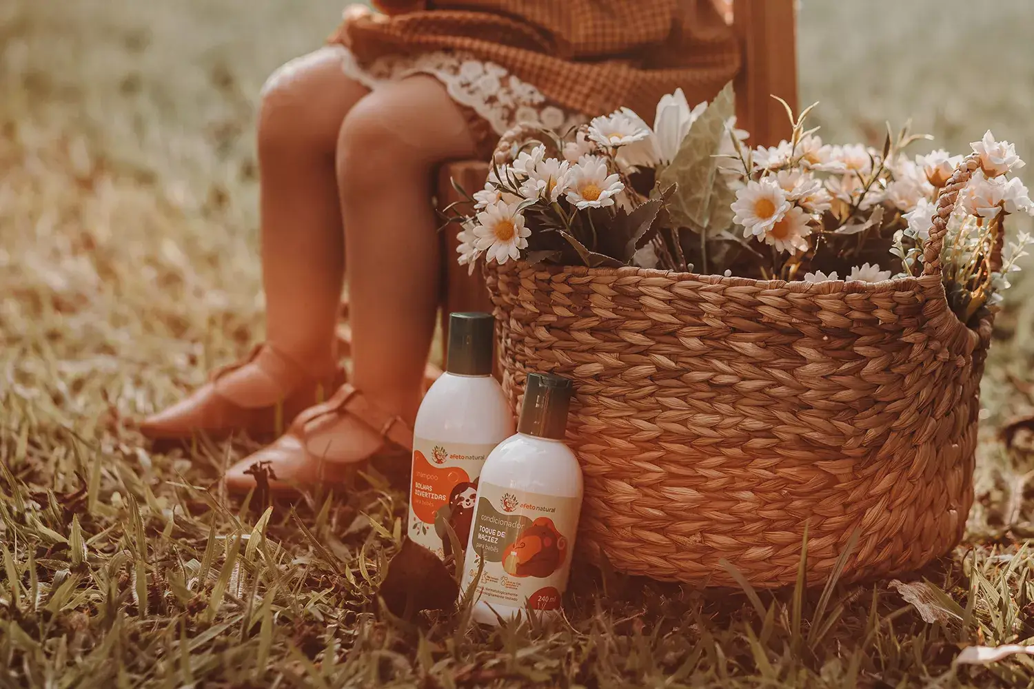 Close de pezinho de criança, ao lado de cesta com flores e produtos da Afeto Natural - Just Real Moms