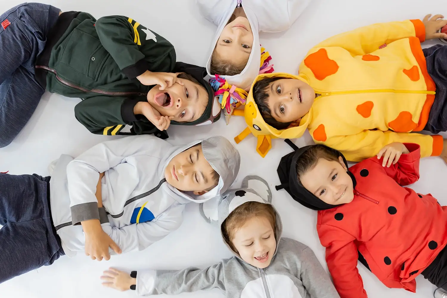 Seis crianças usando fantasias deitadas no chão - Just Real Moms